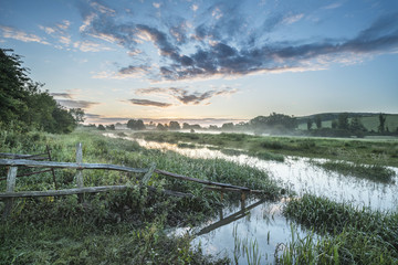 Beautiful vibrant Summer sunrise over English countryside landsc