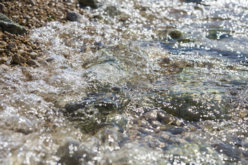 Sea wave on rocky and pebble beach