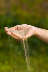 sand running through hand on blurred background