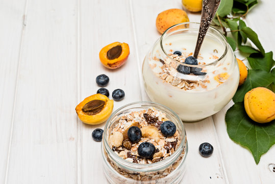 homemade yogurt with apricot, blueberry and muesli on wooden background