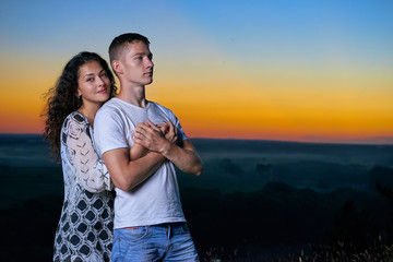 romantic couple portrait at sunset on outdoor, beautiful landscape and bright yellow sky, love tenderness concept, young adult people
