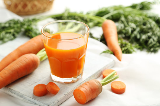 Fresh carrot juice in glass on a white wooden table