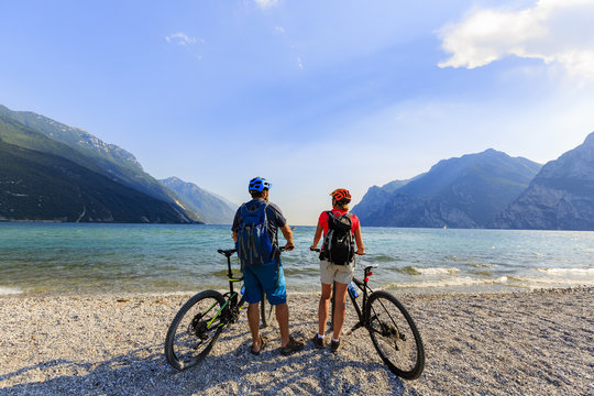 Mountain biking, couple with bikes on Lake Garda, Riva del Garda, Italy