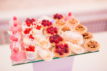 Delicious and tasty dessert table with cupcakes shots at reception closeup