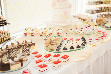 Delicious and tasty dessert table with cupcakes shots at reception closeup