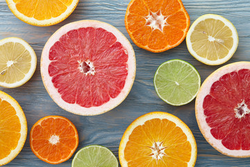 A mix of different citrus fruits cut in half, blue wooden background