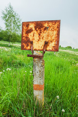 rusty metallic plate on the post in a field