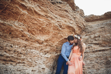 Romantic loving couple walking on the beach with rocks and stones