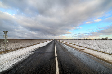 Fototapeta premium Empty paved road, built among agricultural fields.