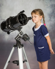 Girl lover of astronomy with interest looks in the eyepiece of the telescope
