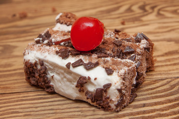 a piece of Chocolate Cake with cherry and cream on the table.