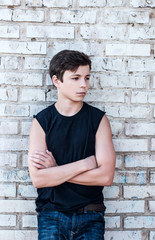 pensive teenager near a brick wall