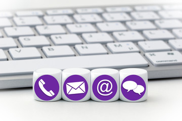 Website and Internet contact us page concept with purple icons on cubes in front of a keyboard