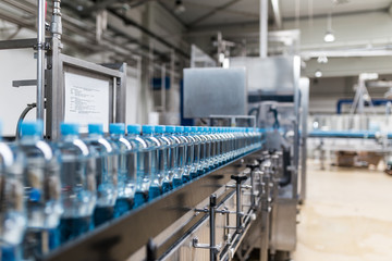 Water factory - Water bottling line for processing and bottling pure spring water into small bottles. Selective focus. - obrazy, fototapety, plakaty