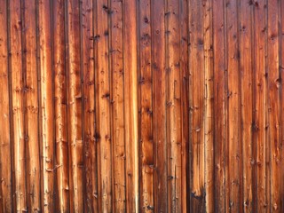 Rotbraun schimmerndes Holz im schönen Licht der Abendsonne als Paneel an der Fassade einer alten...