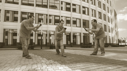 Three men with a mobile phone in front of a white business cente