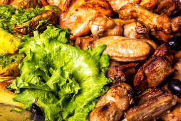 Grilled chicken wings and legs with lettuce and black olives