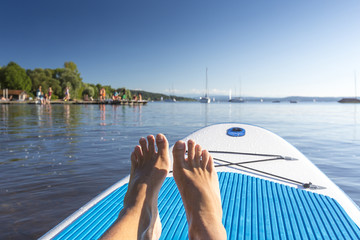 Mann sitzt auf einem SUP-Board auf dem Ammersee