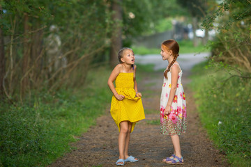 Naklejka na ściany i meble Two little cute girlfriends animatedly talking in the Park.