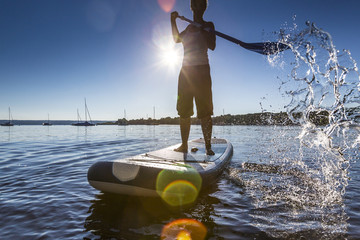 Woman paddleboarding in the lake Ammersee, Bavaria, Germany 

