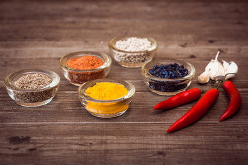 Spices for cooking meat: turmeric, chili pepper, barberry on the wooden table. Horizontal.