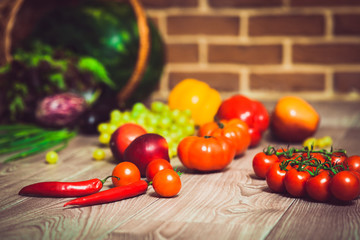 Fresh scattered vegetables and fruits. Overturned basket. Brick wall background. Healthy eatyng concept. Close-up. Warm toned. Horizontal