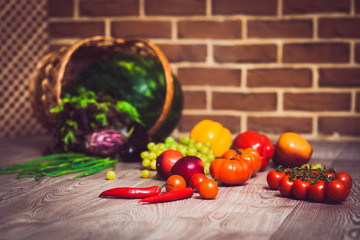 Fresh scattered vegetables and fruits. Overturned basket. Brick wall background. Healthy eatyng concept. Close-up. Warm toned. Horizontal