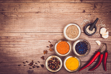 Spices for cooking meat: turmeric, chili pepper, barberry on the wooden table. Top view. Warm toned. Copy space left. Horizontal.