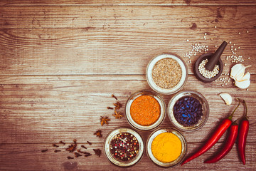 Spices for cooking meat: turmeric, chili pepper, barberry on the wooden table. Top view. Sepia toned. Copy space left. Horizontal.