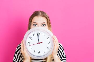 Woman holding clock showing nearly 12