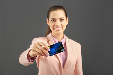 Beautiful businesswoman with credit card on grey background