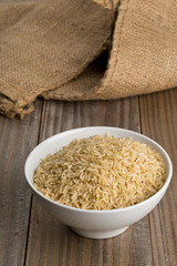 Natural brown uncooked rice in white bowl