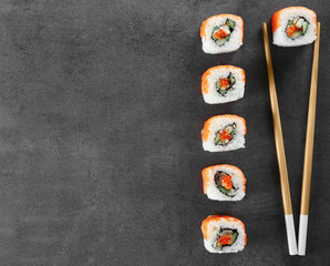 Sushi roll set and chopsticks on dark background