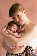 Happy mother holding newborn baby girl in arms