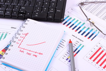 Obraz premium Pen, glasses and computer keyboard on financial graph, business concept