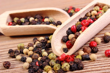 Fresh colored pepper with spoon on wooden background