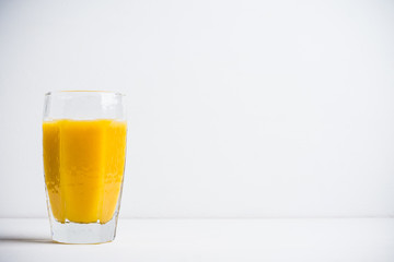 Glass of fresh orange juice on the white wooden background