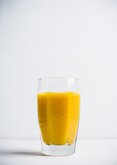 Glass of fresh orange juice on the white wooden background