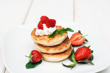 Pancakes with fresh strawberry and cream on white plate. Sweet traditional breakfast for lovers at hotel