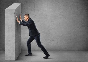 Businessman pushing a concrete wall
