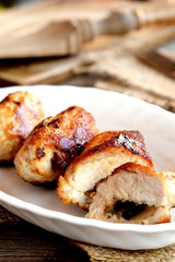 Delicious fried Turkey meat rolls on a plate. Fork, cuisine board on old wooden table. Roasted Turkey breast rolls stuffed with cheese and agaricus. Festive food recipe. Rustic style. Vertical photo