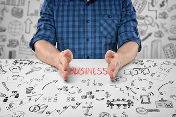 Close-up hands of sitting man with word 'business' between them and doodles around him