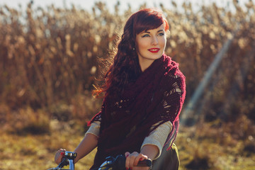 Fototapeta na wymiar Pretty girl riding bicycle in field