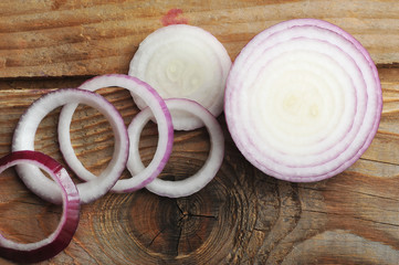 red onions cut into slices on a wooden background