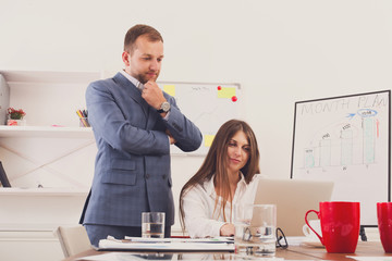 Businessman supervising his female assistant's work on laptop computer