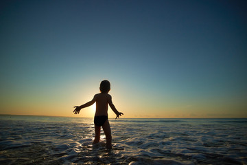 Fototapeta na wymiar boy playing on the beach at sunset