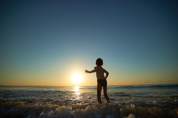 boy playing on the beach at sunset