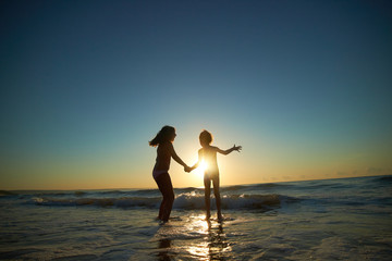 boy and girl on the sea at sunset