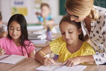 Female teacher helping kids in exercises