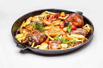 Meat platter with potato slices and braised cabbage. In a large frying pan and a white background